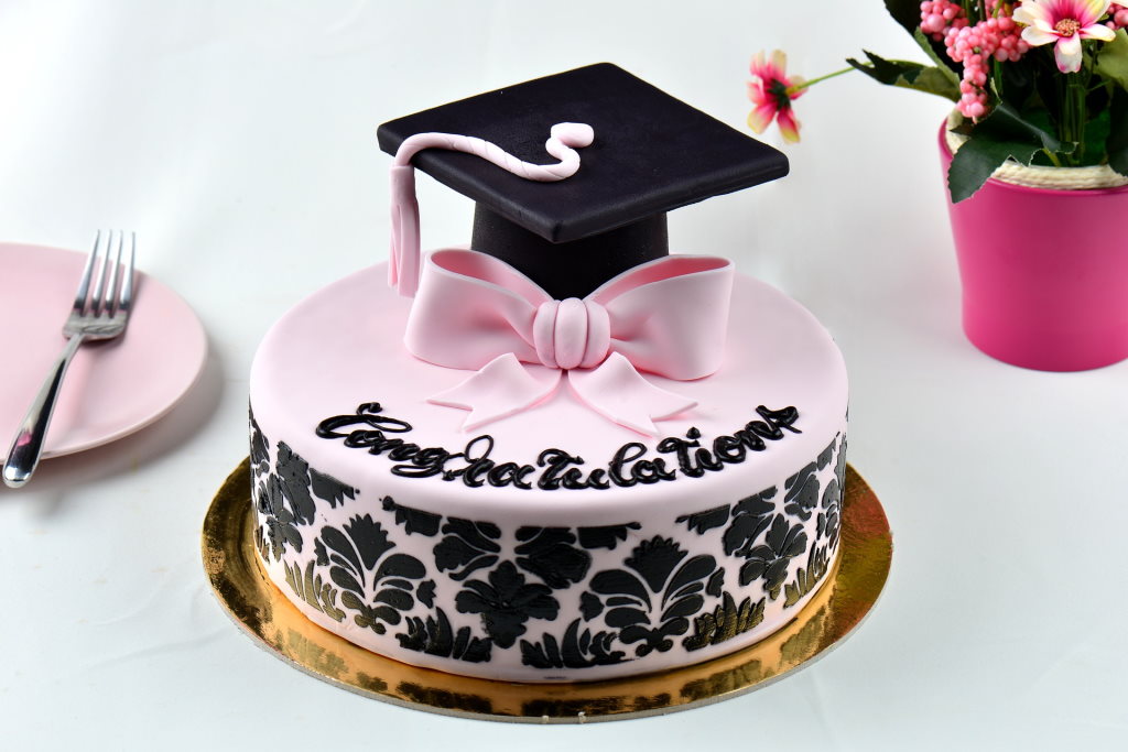 pink and black graduation cake with graduation cap on top