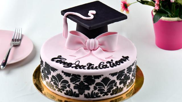 pink and black graduation cake with graduation cap on top